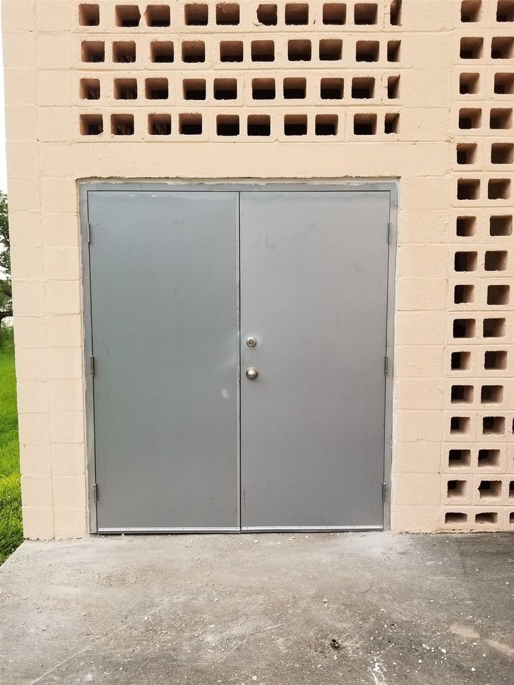 Clean gray pair of hollow metal doors in a tan block wall