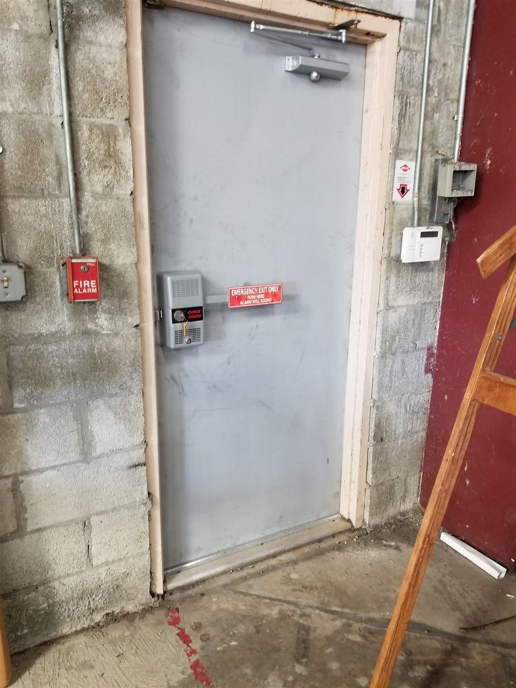 Worn steel back door with old keypad in a block wall