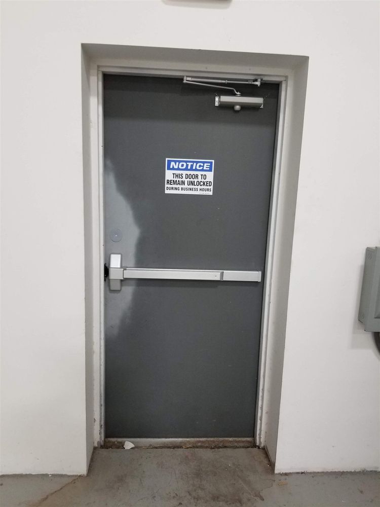 Gray steel exit door with panic bar and posted notice