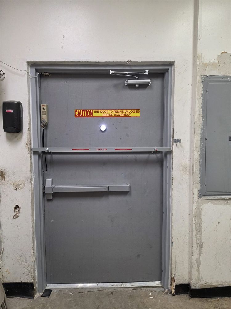 Steel door with exit device, overhead stop and warning label