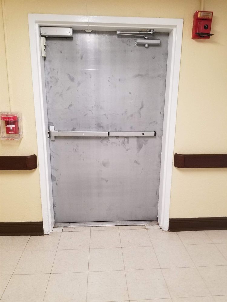 Hollow metal exit door with panic bar beside a fire alarm pull