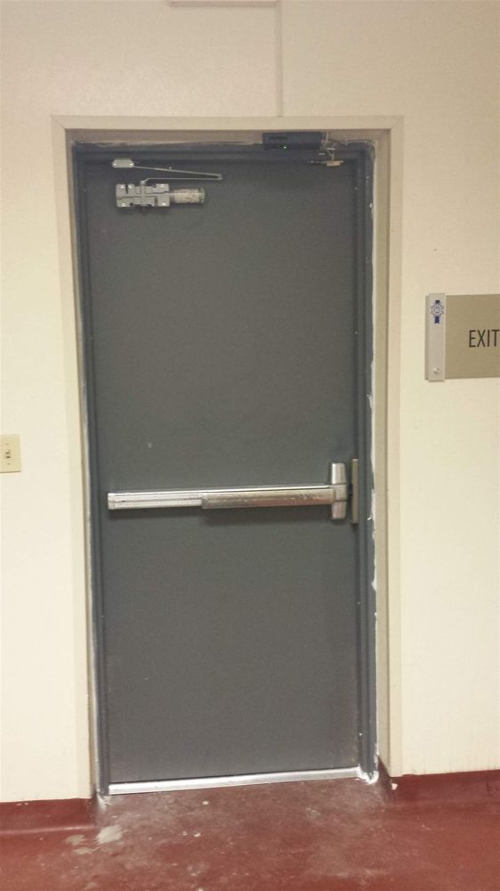 Hollow metal exit door with push bar over a red floor