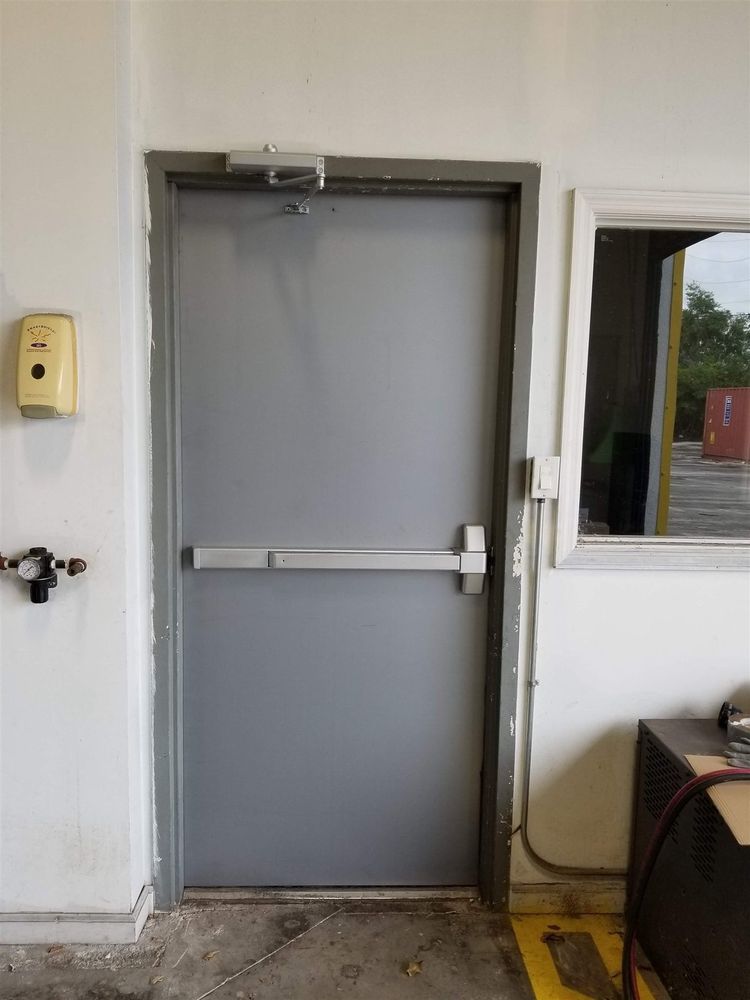 Steel exit door with panic bar next to an office window