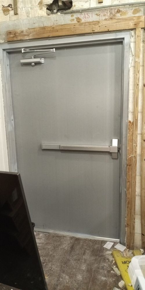 New hollow metal door with panic bar hung in a freshly set frame