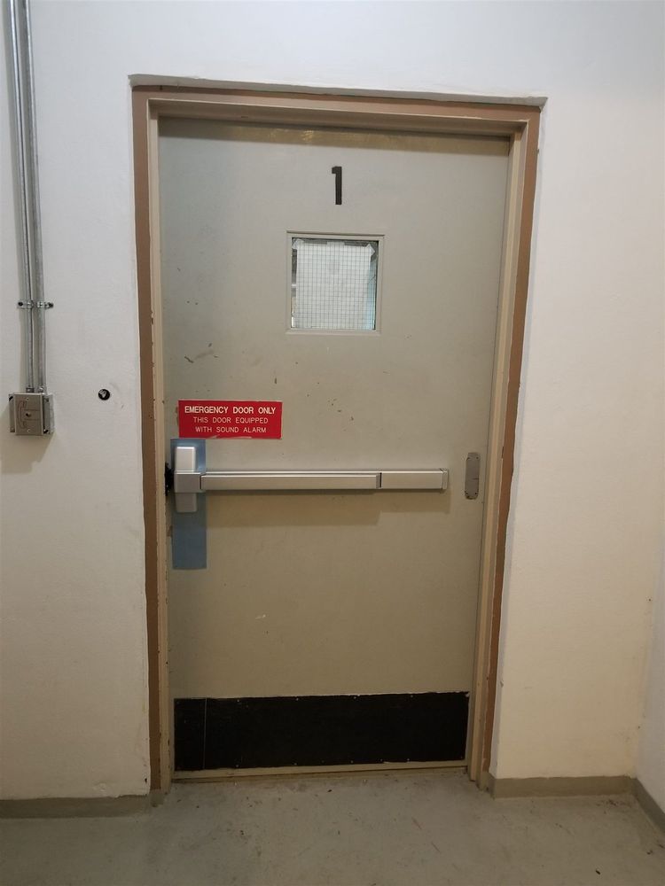 Steel door with vision lite and panic bar in a wood frame