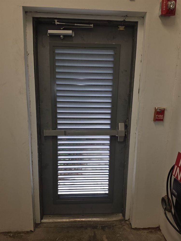 Louvered hollow metal door with panic bar and closer