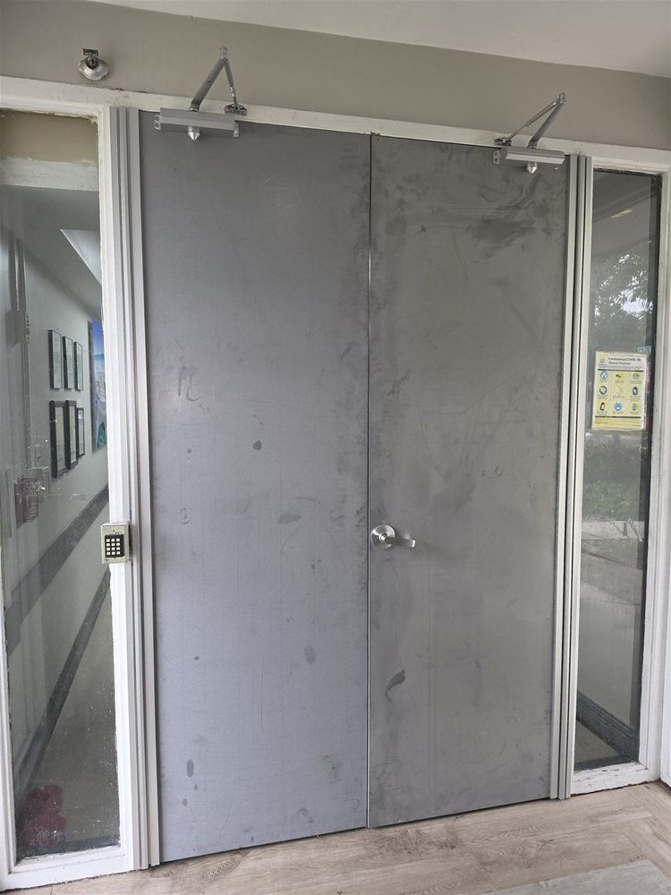 Steel door pair with closers between aluminum storefront sidelites