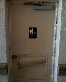 Commercial restroom metal door with damaged bottom louver